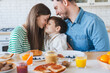 © InsideCreativeHouse - Happy family couple with child little boy having fun with son while sitting on table. Young smiling parents enjoying spending time with kid at the kitchen at home. Care love tenderness concept.