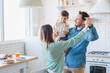 © InsideCreativeHouse - Photo of a happy family of three having fun and dancing with a child boy at kitchen at home. Portrait of young parents spending time together with son. Care and love parenting concept.