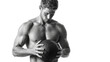 © OCTOLENS - Focused muscular athlete holding medicine ball for workout. strong man shows determination and concentration