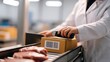 © chusnul - Worker scanning a package in a meat processing facility with raw meat in the foreground and equipment in the background