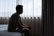 © kieferpix - Silhouette of man looking out window thinking sitting on the bed in the bedroom. Sad man suffering depression insomnia awake and alone on the bed in bedroom.