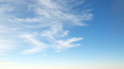 Wall Mural - High altitude cirrus clouds streak gracefully across a clear, pale blue sky with elegant motion movement, slow motion, elegant