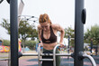 © asier - Woman exercising outdoors, performing dips on parallel bars