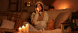 © Pixel-Shot - Sad young woman in warm clothes talking by mobile phone at home during blackout