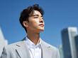 © junga - 파란 하늘을 배경으로 자신감 있게 정장을 입은 젊은 남성의 초상