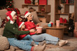 © Pixel-Shot - Little girl and her parents in Santa hats with popcorn watching Christmas movie at home