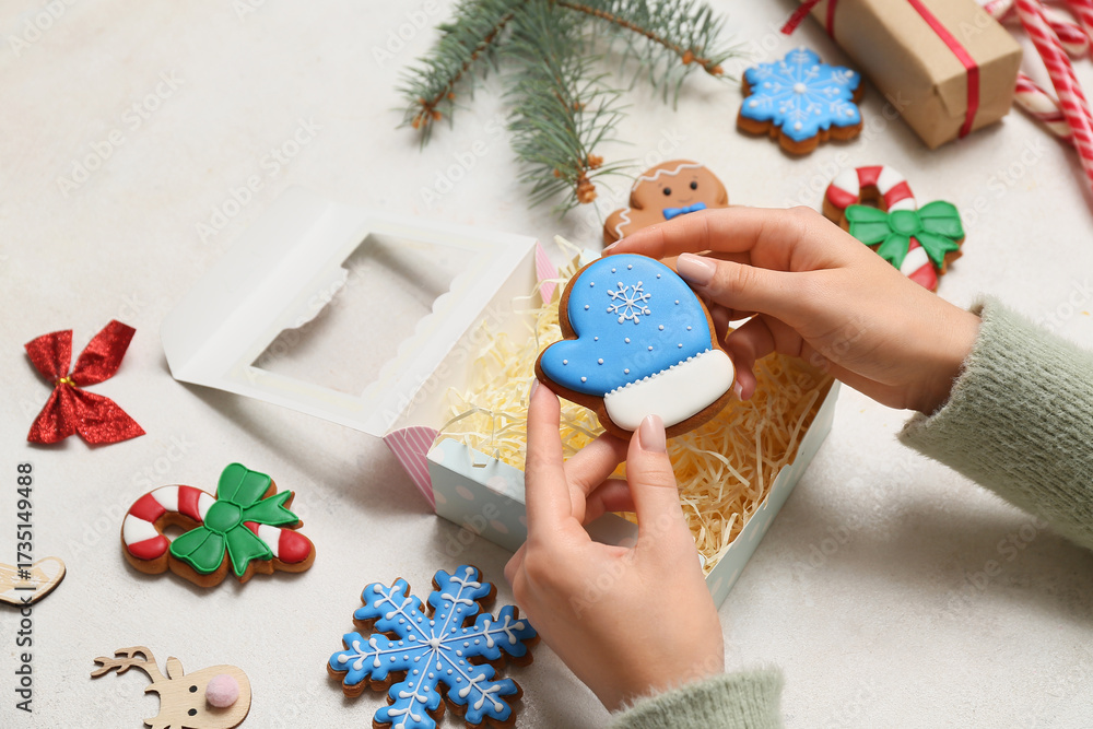Female hands with sweet gingerbread cookies on white background. Christmas celebration