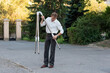 © Vagengeim - Man extends tripod legs to stabilize telescope base. Outdoors, a man dressed in a white shirt and black trousers extends tripod legs to stabilize the base before attaching a telescope