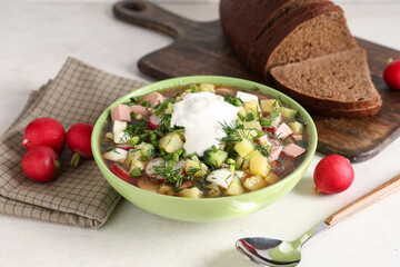 Wall Mural - Bowl of tasty okroshka with sour cream, bread and fresh radish on light background