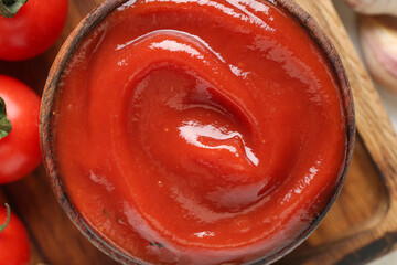 Wall Mural - Bowl with tasty ketchup on wooden tray as background, closeup