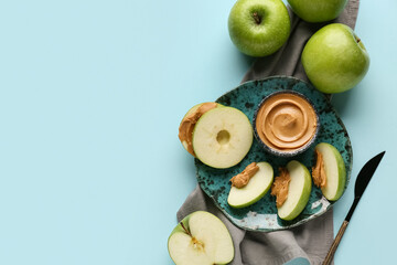 Wall Mural - Plate of fresh apple slices with sweet peanut butter on blue background