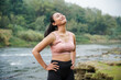 © Nasrul Ma Arif - A slender, tanned Asian girl in sportswear is doing neck roll stretching exercises in the open air on the edge of a beautiful river, before exercising.