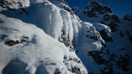 Wall Mural - deep shadows and bright highlights on a snow-covered rock formation, dramatic side light, slow push 