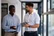 © Zoran Jesic - Two businessmen discussing work ideas in office hallway