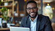 © tu - Smiling businessman in glasses and suit working on laptop in modern office, professional talent agent managing contracts, bookings, and career opportunities.