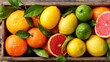 © Babb - Bright oranges lemons limes and grapefruit are displayed in a wooden box presenting a vibrant mix of colors and textures. Fresh leaves enhance the visual appeal.