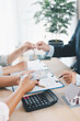 © doidam10 - Close up of real estate agent handing house key to client with contract paperwork, calculator and house models on desk, concept of home ownership, mortgage loan, property investment and success.