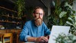 © iuricazac - Man using laptop at indoor plant-filled space.
