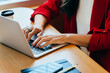 © (JLco) Julia Amaral - Woman typing on a laptop while wearing a red blazer at a desk
