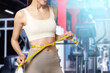 © New Africa - Athletic woman with flat belly and measuring tape in gym, closeup