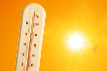 Wall Mural - thermometer showing high temperature against orange sky with bright sun. extremely hot weather