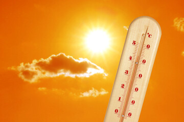 Wall Mural - thermometer showing high temperature against orange sky with bright sun and clouds. extremely hot we