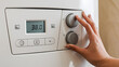 © Mst Rozina Pervin - Close-up of a hand adjusting the temperature control on a white heating unit, maintaining comfort