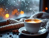 Filiżanka gorącej, parującej kawy, obok koc i ziarna kawy