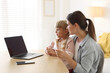 © New Africa - Telehealth. Mother and her daughter having online consultation with doctor via laptop at table indoors