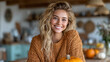 © ArtShop - Young woman smiling while sitting in cozy sweater with pumpkin at home