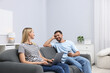 © New Africa - Happy couple with devices spending time together on sofa at home