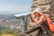 © EdNurg - Young woman exploring historical site, using binoculars to admire scenic landscape from ancient fortress, enjoying travel and discovery
