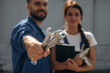 © standret - Holding tools and digital tablet. Cheerful male and female mechanics are standing outdoors together