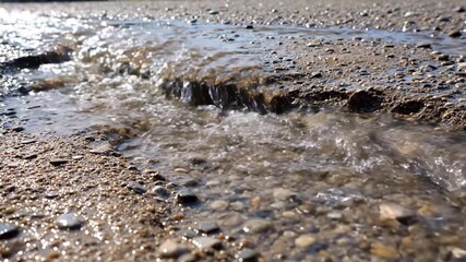 Wall Mural - Close-up of rapid rainwater runoff flowing over an unpaved, textured ground, creating small rivulets and erosion patterns under bright light ground, nature, flow
