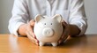 © Visi Hue - Saving money concept with piggy bank held by person for financial planning and investment growth