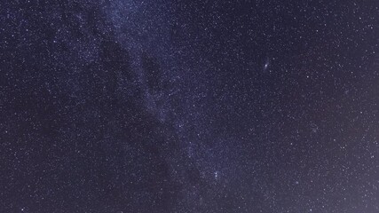 Wall Mural -  Starry sky timelapse background. Beautiful night sky with Milky Way galaxy on dark sky.
