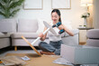 © wattana - Smiling young woman assembling round table with electric drill at home, enjoying DIY project.