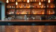 © miss irine - Empty bar counter top surface with blurred shelves of alcohol bottles in background. Dim lighting from hanging bulbs sets cozy mood. Modern pub interior scene ready for drinks.