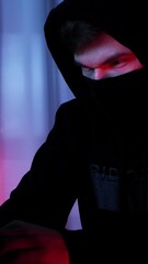 Man in black mask looking at laptop screen and typing on keyboard.Vertical video