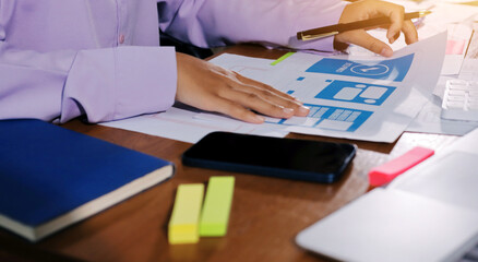 Close up ux developer and ui designer brainstorming about mobile app interface wireframe design on table with customer breif and color code at modern office.Creative digital development agency.