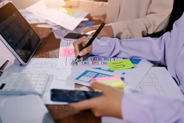 Close up ux developer and ui designer brainstorming about mobile app interface wireframe design on table with customer breif and color code at modern office.Creative digital development agency.