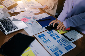 Close up ux developer and ui designer brainstorming about mobile app interface wireframe design on table with customer breif and color code at modern office.Creative digital development agency.