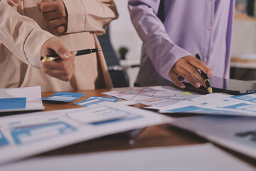 Close up ux developer and ui designer brainstorming about mobile app interface wireframe design on table with customer breif and color code at modern office.Creative digital development agency.