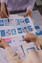 Close up ux developer and ui designer brainstorming about mobile app interface wireframe design on table with customer breif and color code at modern office.Creative digital development agency.