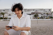 © ADDICTIVE STOCK - Young man enjoying technology on a beach at sunset