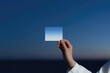 © Maria - Hand holding transparent square against serene blue sky at dusk