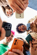 © Xavier Lorenzo - Vertical shot. Close up low angle of young students hands holding mobile phones in a circle. Social media and technology lifestyle