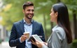© li - Businessman holding coffee and tablet talking to businesswoman outdoors. High quality