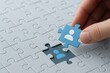 © Haseeb - Hand placing blue puzzle piece with person icon into missing slot symbolizing recruitment