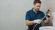 © Vyatcheslav - Professional plumber repairing a toilet in a bathroom. Male worker in uniform using a tool on a pipe. Home maintenance service with copy space.